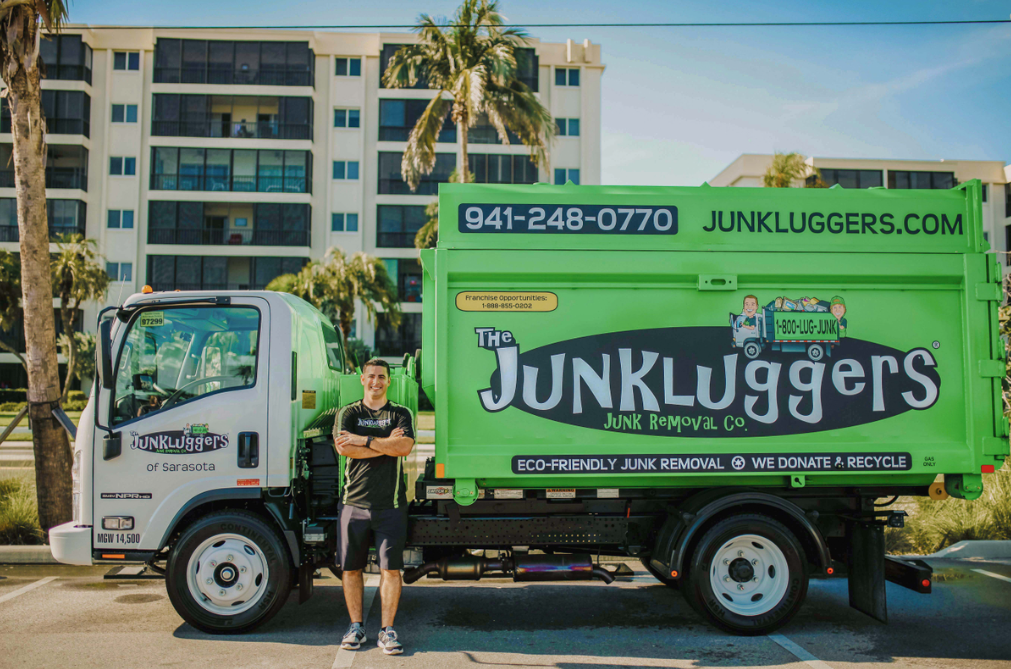 person in front of green truck with palm trees in the background